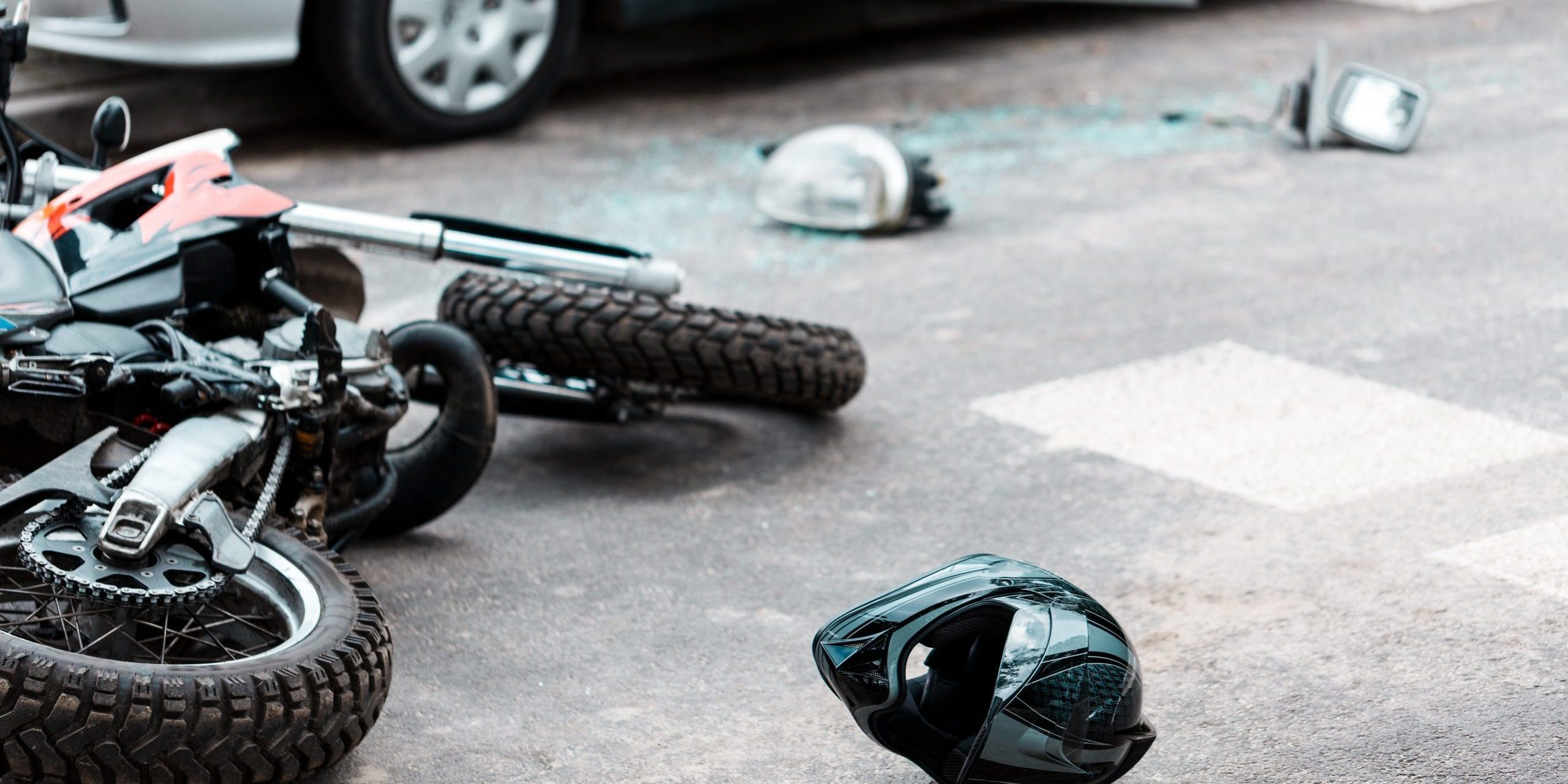 Overturned motorcycle and helmet on the street after collision with a car